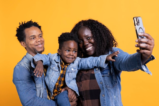 cheerful african american family taking pictures against yellow background