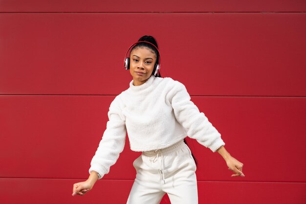 Cheerful african american girl dressed in sportswear listening to music on headphones