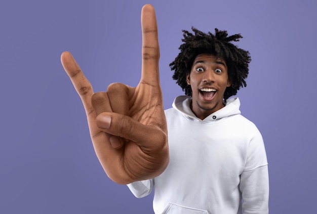 Cheerful african american guy showing handhorns gesture