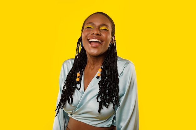 Cheerful african american lady laughing out loud over yellow background