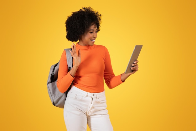 Cheerful african american woman waving during a video call on a tablet