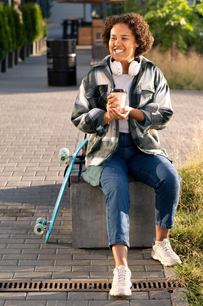 Photo cheerful african teenage skateboarder with drink