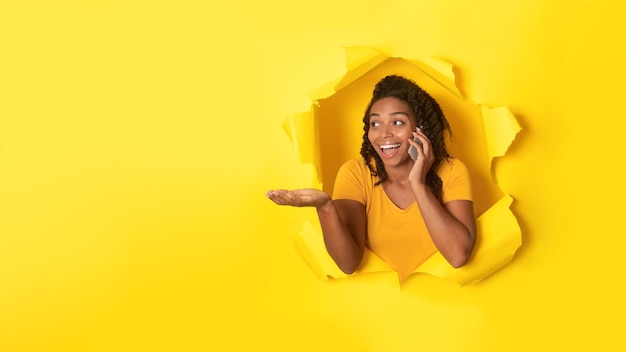 Cheerful African Woman Talking On Phone In Torn Yellow Paper