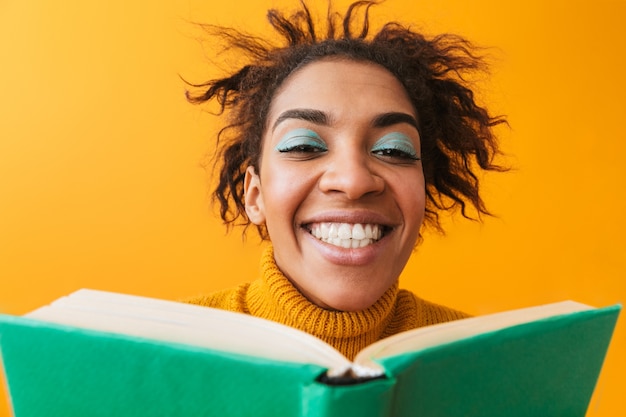 Photo cheerful african woman wearing sweater holding a book isolated