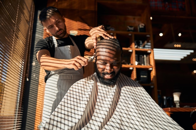 Cheerful Afro American man getting haircut in barbershop