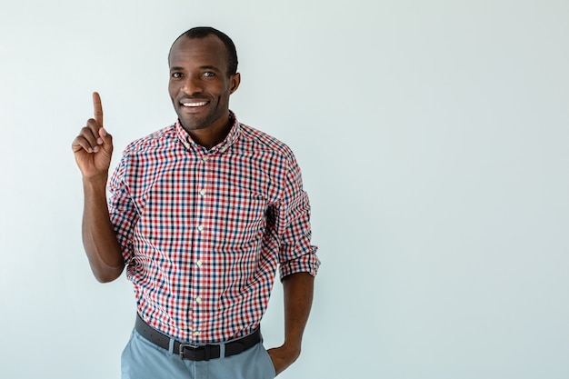 Cheerful afro american man making recommendations while standing against white wall