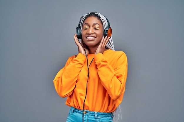 Donna afro americana allegra con gli occhi chiusi che ascolta musica in cuffia