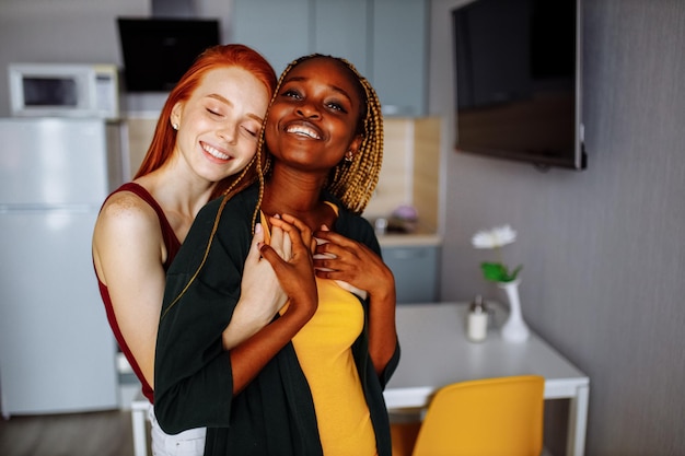 Cheerful afro and european lesbian women at home on the bed