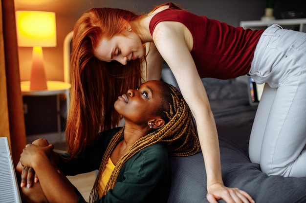 Cheerful afro and european lesbian women at home on the bed