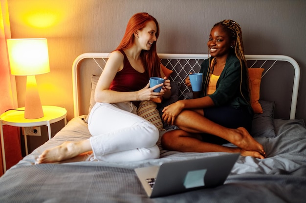 Cheerful afro and european lesbian women at home on the bed