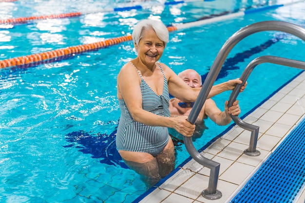 Cheerful aged couple coming out from the indoor pool healthy lifestyle concept