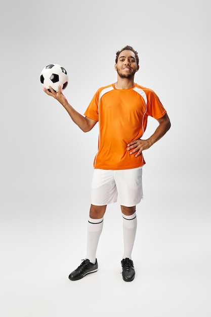 cheerful appealing african american sportsman posing happily with football and looking at camera