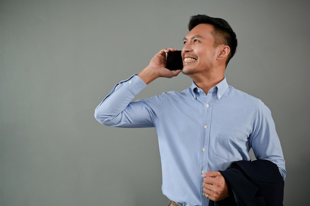 Cheerful Asian businessman talking on the phone isolated gray background