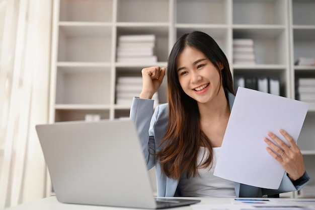 Cheerful Asian businesswoman rejoicing and celebrating her project success