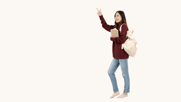 Жизнерадостная азиатская студентка колледжа указывает пальцем в направлении, куда она идет.