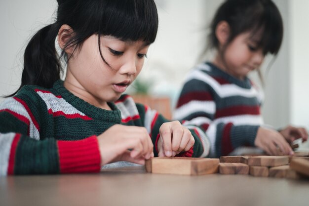 木製のビルディングブロックで遊ぶ陽気なアジアの女の子。楽しんで、創造性を学びます。スマートキッドコンセプト。