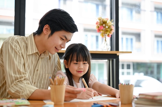 Cheerful Asian male art teacher is teaching to his young female student