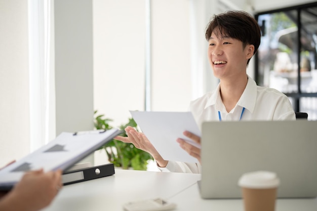 A cheerful Asian male office worker discusses work and shares his ideas with a female colleague