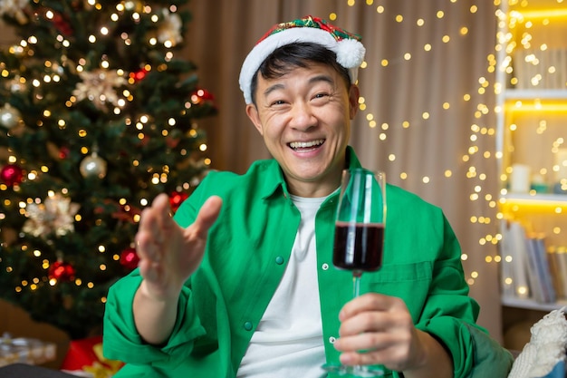 Cheerful asian man on christmas and new year greeting friends man talking on video call with