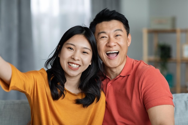 陽気なアジアの男性と女性が自宅で一緒に自撮りをする