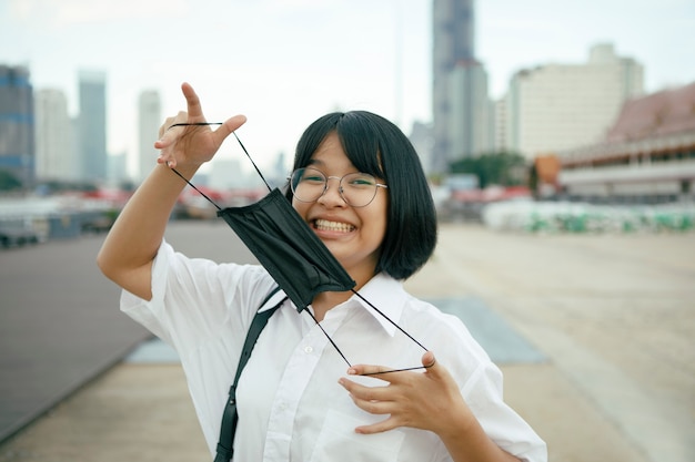 Photo cheerful asian teenager with protection face mask in hand