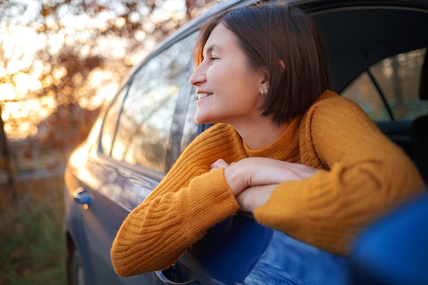 日没の車の中で陽気なアジアの女性