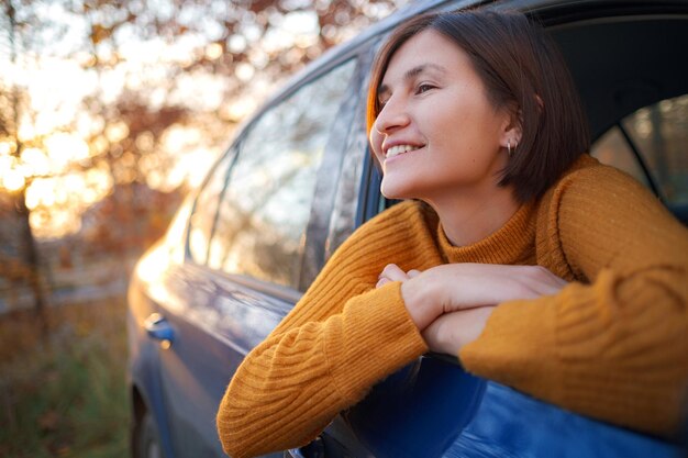 日没の車の中で陽気なアジアの女性