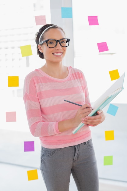 Cheerful attractive artist writing on her sketchpad