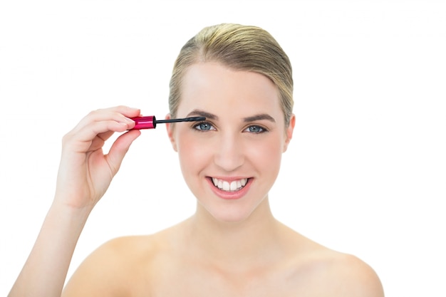 Cheerful attractive blonde applying mascara