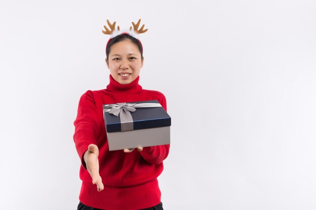 Cheerful attractive woman in red dress having fun while sitting on the big gift box isolated on a white background