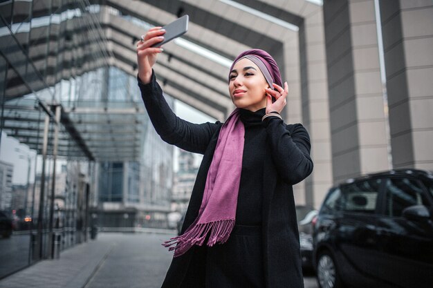 Cheerful and attractive young woman in hijab taking selfie.