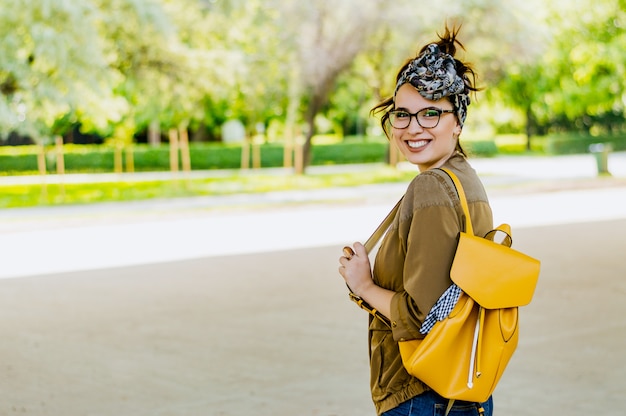 Веселая привлекательная молодая женщина с желтым рюкзаком