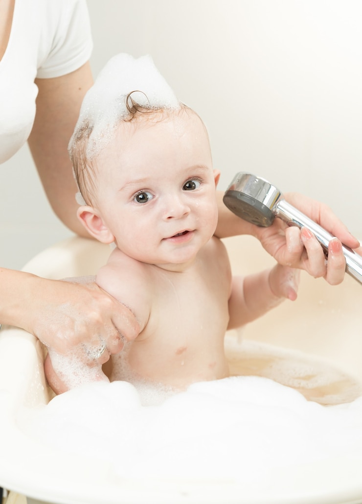 Photo cheerful baby boy playing with shower head in bath