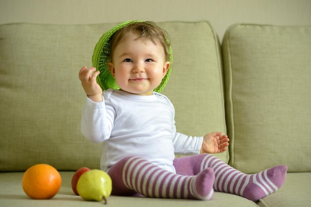 Cheerful baby girl plays with dish and fruit