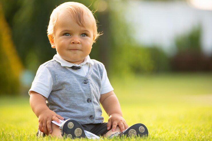 A cheerful baby is sitting on the lawn
