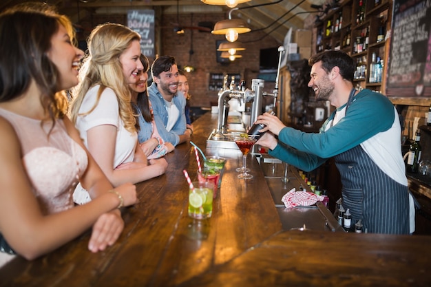 Cheerful bartender interacting with customers while making drink