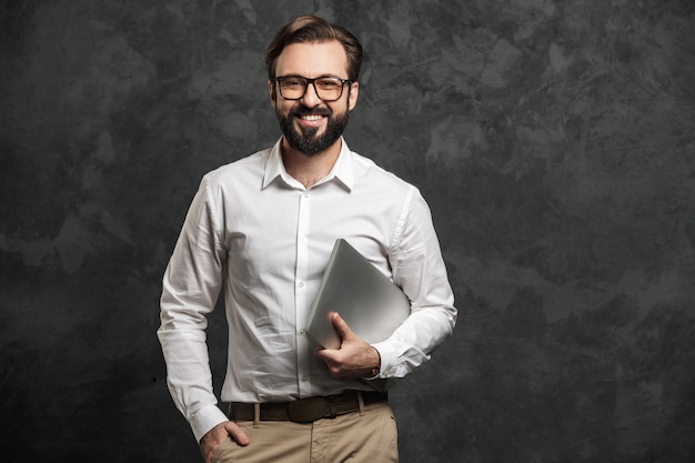 Cheerful bearded businessman holding laptop computer