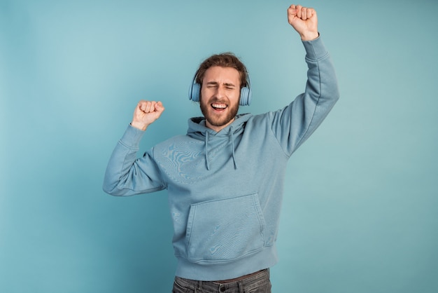 Cheerful, bearded man raised his sleeve, he is in headphones, listening to music. Man   dancing, having fun