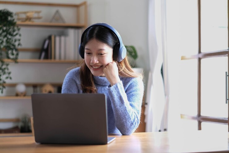 Photo 楽しい美しいアジア人女性ヘッドフォンをかぶってデジタルタブレットを見ているビデオコール会議でインターネットでオンラインで勉強している