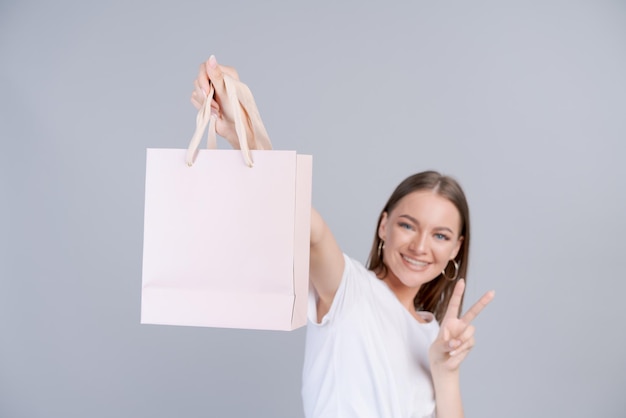 Cheerful beautiful girl holding shopping bag with place for mock up isolated