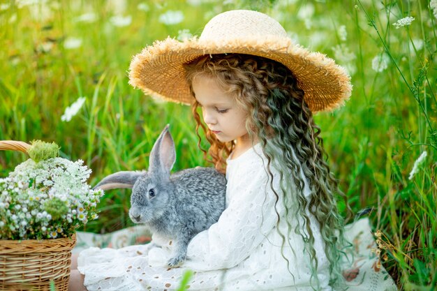 Cheerful beautiful girl in a straw hat in a yellow field with flowers