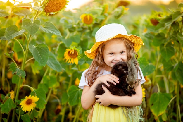 Cheerful beautiful girl in a straw hat in a yellow field with flowers