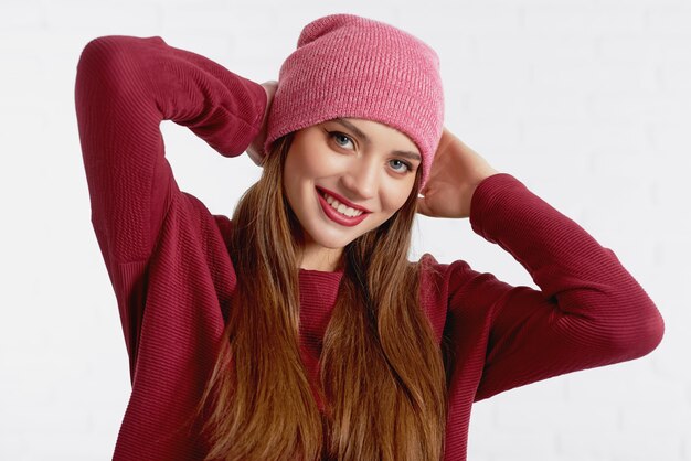 Cheerful beautiful model in red hat and sweater with eye make up and red lipstick 