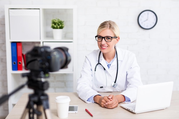 Photo cheerful beautiful woman doctor recording vlog video about medicine