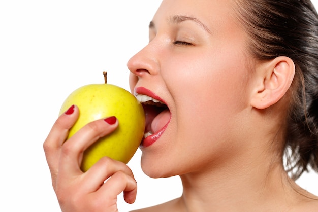 Cheerful beautiful woman eating apple isolated over white background