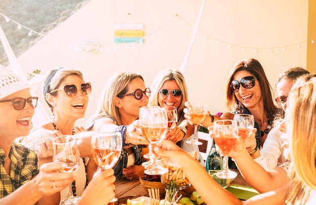 Cheerful beautiful young women toasting wine together, celebrating and having fun