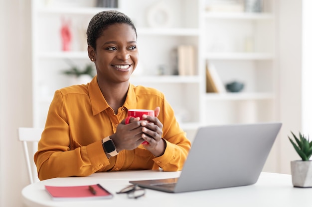 Cheerful black lady employee having coffee break at office