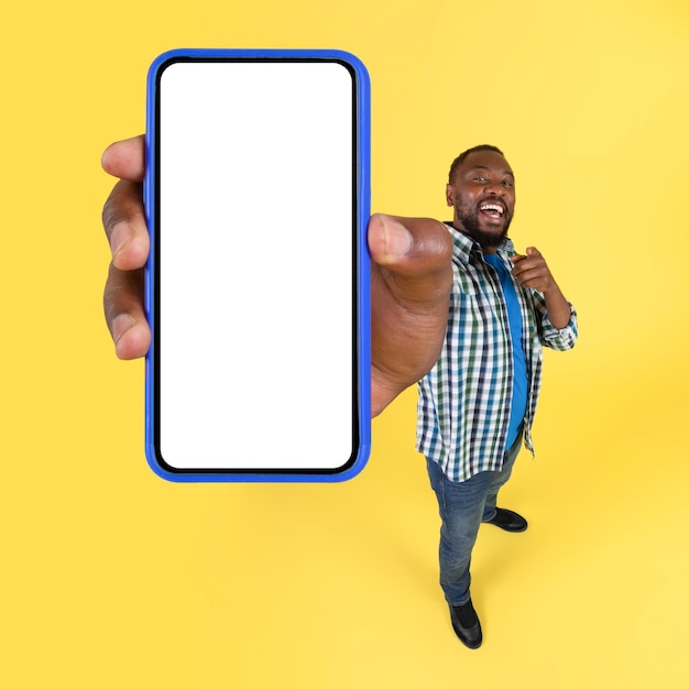 Cheerful Black Male Showing Huge Smartphone Over Yellow Background Square