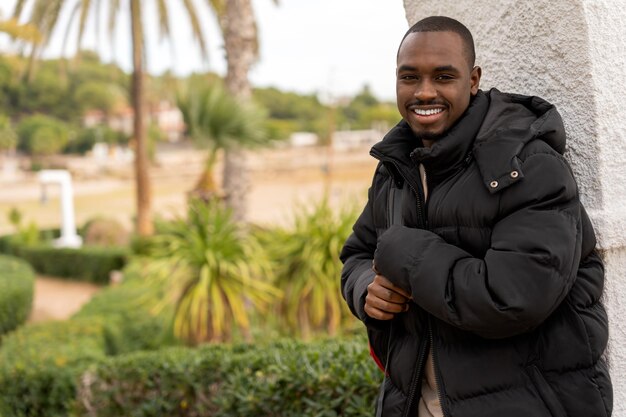 Cheerful black man in warm jacket at park