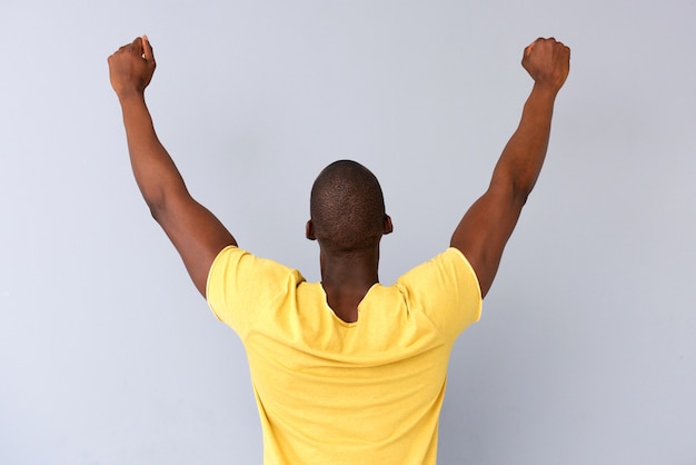 Behind of cheerful black man with arms raised 